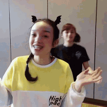 a woman wearing a bat headband and a yellow sweater with the word high on it