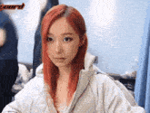a woman with red hair is wearing a white jacket with the word board in the background