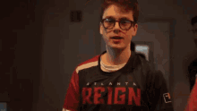 a man wearing glasses is making a funny face in front of a television screen .
