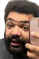 a man with a beard is taking a picture of himself with his phone