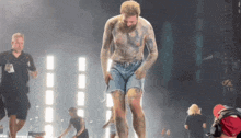 a man with a lot of tattoos on his body is dancing on stage