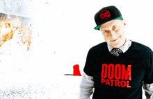 a man wearing a doom patrol shirt and a hat