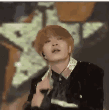 a young man in a suit and tie is holding a microphone in front of a large star .