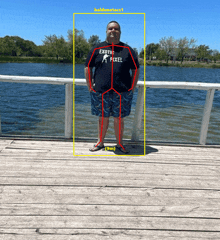 a man wearing an exotic pixel shirt stands on a wooden dock