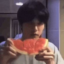 a man is eating a slice of watermelon with a knife .