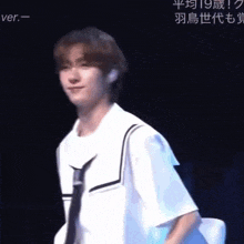 a young man wearing a white shirt and black tie is standing on a stage .
