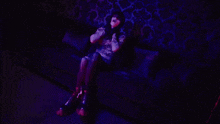 a woman is sitting on a couch in a dark room with a purple light behind her .