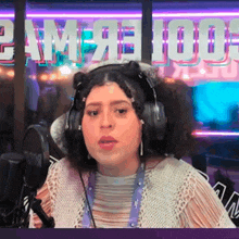 a woman wearing headphones stands in front of a microphone in front of a sign that says ' camp 100 '