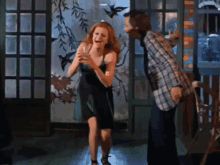 a woman in a black dress is holding a glass and laughing with a man in a plaid shirt