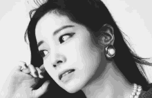 a black and white photo of a woman wearing earrings and a pearl necklace