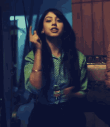a woman wearing a green polka dot shirt is sitting in a dark room