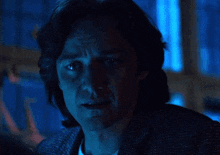 a close up of a man 's face with his eyes closed in a dark room with blue lights behind him .