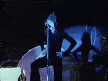 a woman singing into a microphone with a drum in the background