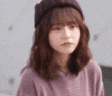 a close up of a woman wearing a hat and a purple hoodie .