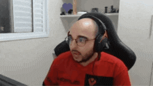 a bald man wearing glasses and headphones is sitting in a chair in front of a computer