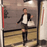 a woman in shorts and boots is standing in a doorway holding a white bag