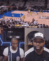 a man wearing a raiders hat watches a basketball game on tv