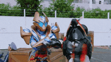 a man in a blue and gold armor is standing next to another man in a black armor