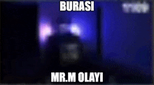 a blurry picture of a person standing in front of a blue wall with the words burasi mr.m olayi on it .