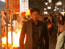 a man in a suit walks down a street with chinese writing on a sign
