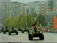 a row of military vehicles are driving down the street