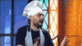 a man wearing a chef 's hat and apron is holding a kebab in his hand .