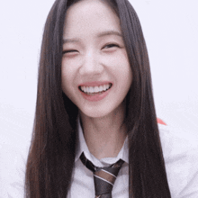 a woman with long hair wearing a white shirt and tie smiles