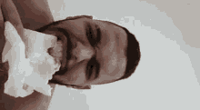 a man with a beard is holding a napkin in his mouth and eating it .