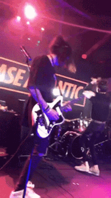 a man is playing a guitar on stage in front of a sign that says atlantic