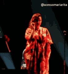 a woman in a red dress singing into a microphone on a stage