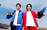 two men in blue and red jackets holding weapons in front of a stadium