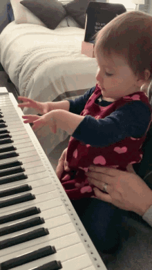 a little girl is playing a piano with a book behind her that says we are neither here nor there