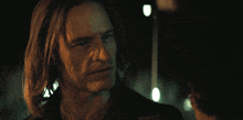 a man and a woman looking at each other in a dark room