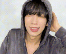 a young man wearing a hoodie is smiling and holding his hair .