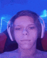 a young man wearing headphones looks at the camera with a purple background behind him .