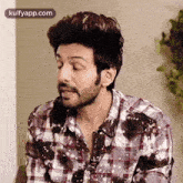 a man with a beard is wearing a plaid shirt .