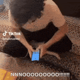 a man is kneeling down on the floor playing with a cell phone .