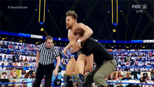 a wrestler is being lifted in the air by a referee during a smack down match