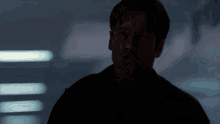 a man in a black jacket is standing in a dark room