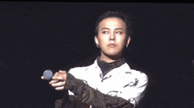 a man in a white shirt holds a microphone in his right hand