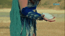 a woman in a blue costume is holding something in her hand with gma in the background