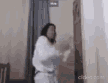 a woman in a white robe is standing in a room .