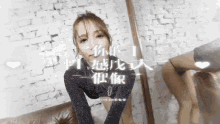a woman sitting on a couch in front of a brick wall with chinese writing