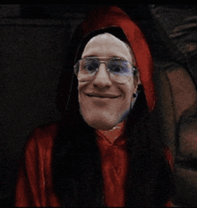 a man wearing glasses and a red robe smiles for the camera