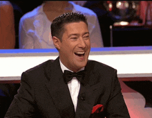 a man in a tuxedo with a bow tie is smiling