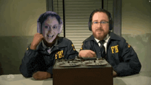 a man and a woman in fbi uniforms are sitting at a desk