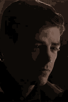 a close up of a man 's face in the dark with a light behind him .