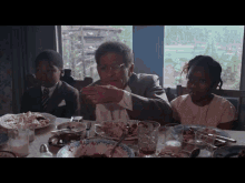 a man and two children sit at a table with plates of food and glasses
