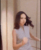 a woman is dancing in front of a mirror and her hair is blowing in the wind