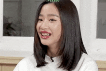 a woman wearing red lipstick and a white shirt smiles